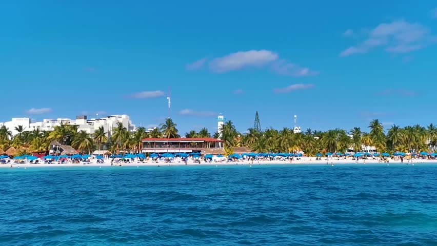 Isla Mujeres Womens Island panorama view from speed boat to tropical beach pier jetty resorts hotels boats people and palm trees in Caribbean Sea Cancun Quintana Roo Mexico.