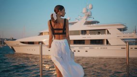 Dreamy woman looking ocean beauty on evening waterfront. Gorgeous brunette lady relaxing on pier with moored luxury yacht. Elegant tanned girl enjoy calm summer weekend on embankment. Vacation concept - Powered by Shutterstock - Get 15% off with code: PIKWIZARD15