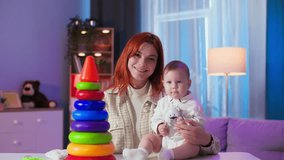 portrait of young woman with a small child playing with educational toys while recording a video blog for social networks while sitting at home