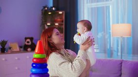 caring female parent having fun playing with little child tossing her top and catching her with hands while standing in cozy room