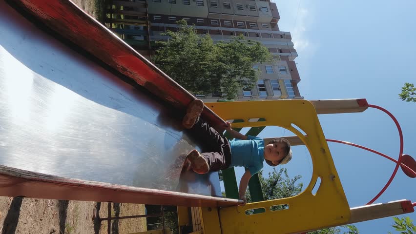 Vertical video of a boy on a high playground, looking down. Concepts about fear, sports, physical activity, slipping, falling, pain, motor coordination, skills, emotions, communication, loneliness Royalty-Free Stock Footage #3453452143