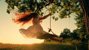 Child plays on wooden swing, dreams of fly. Child swing, kid girl smile in flight. Child girl Happiness dream entertainment. Happy little girl swings on swing in park under tree at sunset. Family walk - Powered by Shutterstock - Get 15% off with code: PIKWIZARD15
