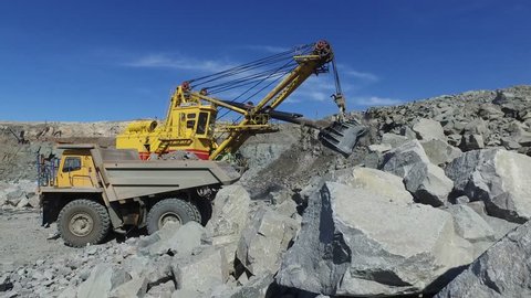 Mining. excavator loading granite or ore into dump truck