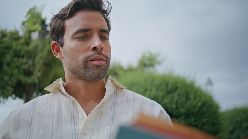 Groomed man reading novel aloud at summer park closeup. Handsome brunette relaxing greenery city square enjoying book alone. Unshaven tanned macho resting at fresh air calm nature. Hobby concept Royalty-Free Stock Footage #3453482117