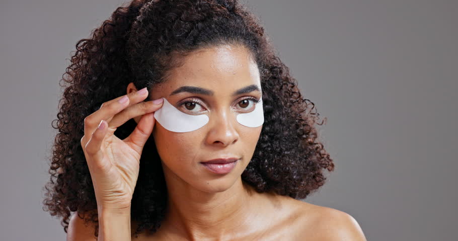 Face, beauty and eye mask with woman in studio on gray background for antiaging, cosmetics or wellness. Portrait, skincare and treatment with confident young model proud of natural dermatology Royalty-Free Stock Footage #3453495667
