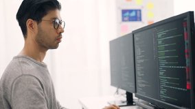 Side profile of an Asian male software developer working attentively on complex code across triple monitors in a bright office. - Powered by Shutterstock - Get 15% off with code: PIKWIZARD15