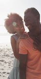 Vertical video of portrait of happy african american couple on sunny beach. spending free time at beach holiday.