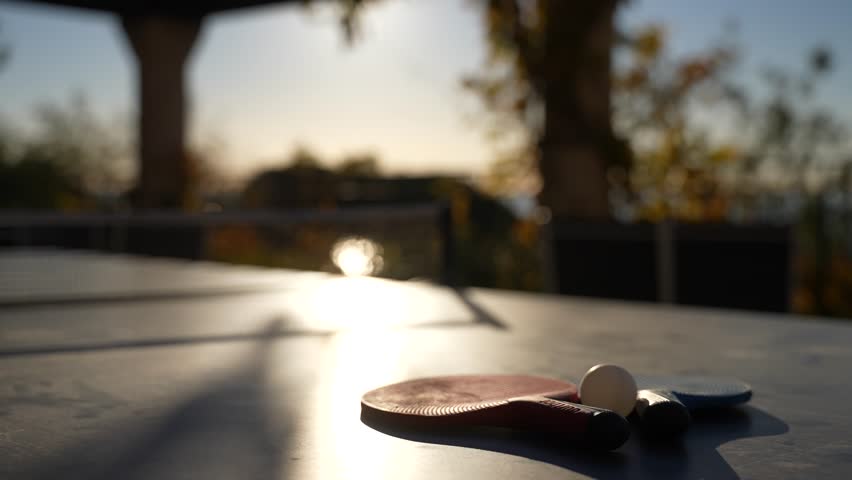 Ping pong table with paddles located on a terrace in Cannes France with sun shining, Close up handheld shot