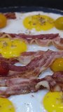 A Mouth Watering Fried Bacon, Eggs, Yellow and red Cherry Tomatoes are steamingly cooking on the Stove at Home 