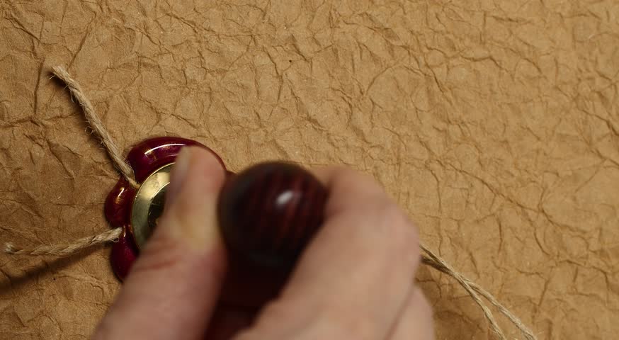 Red and golden wax seal, vertical vintage wax stamp with rope on brown old paper