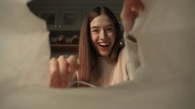 A woman is captured in a moment of joy when she opens a paper bag, eagerly stretching out her hands to the contents. - Powered by Shutterstock - Get 15% off with code: PIKWIZARD15