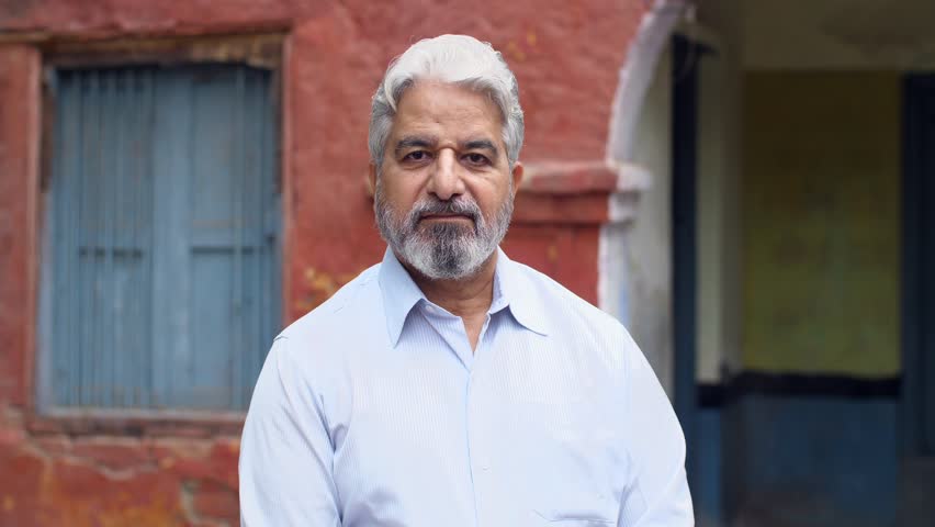 Grey-haired old man dressed in formal wear giving a toothy smile - happy, grand father, father in law. Portrait shot of a successful old businessman standing cheerfully outside an old government sc...