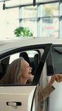Mature Caucasian couple hugging with happiness while buying a new car. Vertical video. 