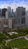 Beautiful green Millennium Park locating among the stunning skyscrapers. Drone flying over the central square with Bean Sculpture and numerous tourists. Vertical video.