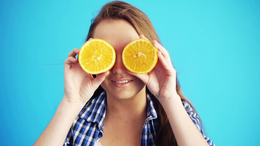 young beautiful woman holding oranges and smiling to camera