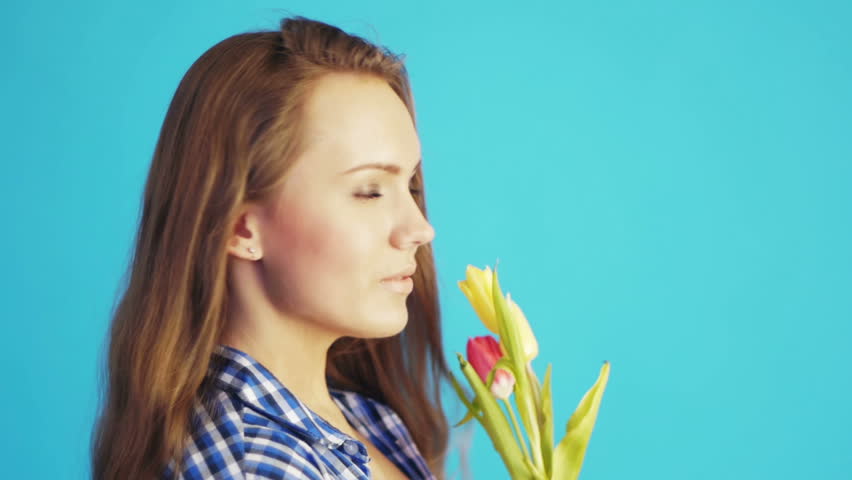 young woman sniffing tulips and smiling