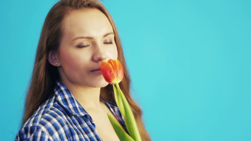 young woman sniffing red tulip and smiling