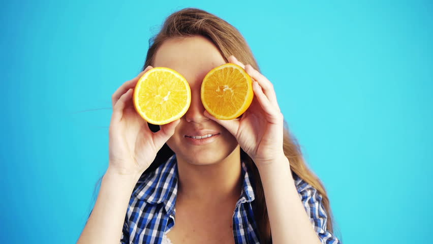 young woman playing with oranges and smiling