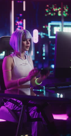 Vertical Screen: Young Woman in Futuristic Cosplay Clothes Sitting Down to Play Video Games on a Computer. Beautiful Girl Putting On Headphones and Talking to Players. Streaming and Gaming Concept Royalty-Free Stock Footage #3453745885