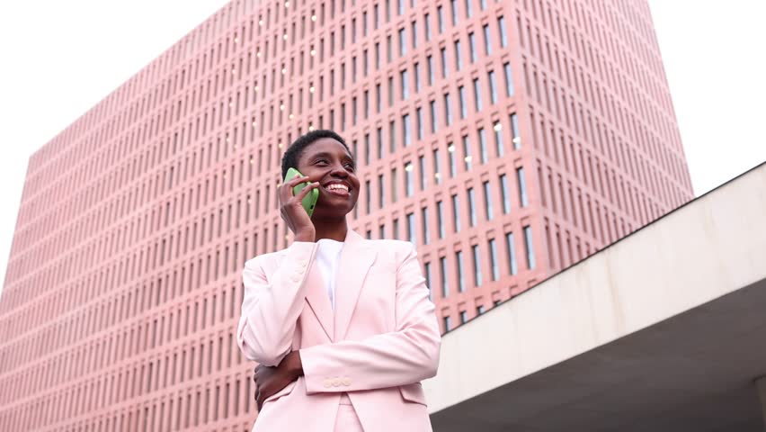 Young african businesswoman talking on a mobile phone in finantial district. Young successful black businesswoman using a phone in the street