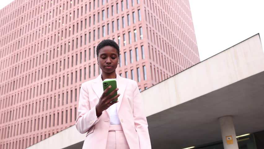 Young black businesswoman talking on a mobile phone in finantial district. Young successful black businesswoman using a phone on the street.