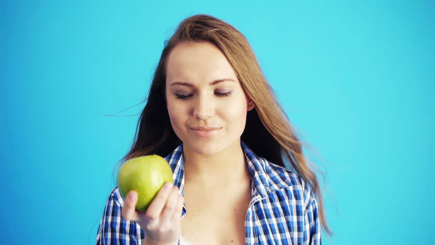woman eating green apple and smiling