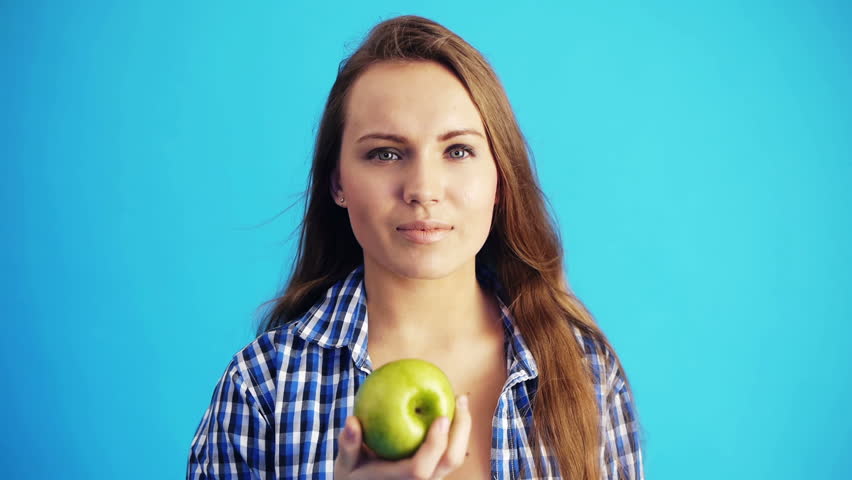 young woman holding green apple and smiling