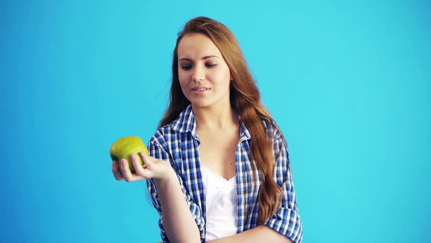 young woman holding green apple and smiling