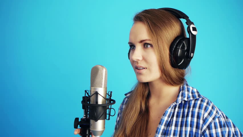 woman singing with headphones at studio