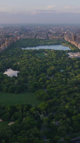 Vertical Screen: New York Cityscape at Sunset. Aerial Footage from a Helicopter. Modern Skyscrapers Around Central Park in Manhattan Island. Focus on Nature, Trees and Lakes in the Park in the City