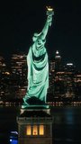Vertical Screen: Panoramic Aerial Footage of an American Symbol of Freedom. Cinematic Helicopter Pass by the Statue of Liberty at Night. Landmark New York Monument with Manhattan Skyscrapers