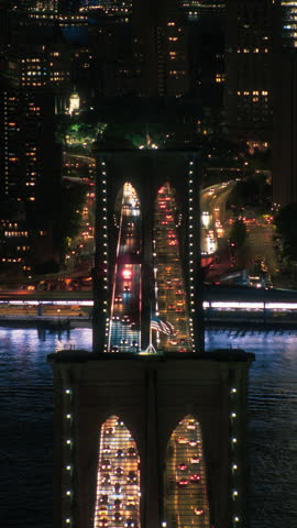 Vertical Screen: New York City Skyline from a Helicopter at Night. Famous Skyscraper Buildings and Brooklyn Bridge with Illuminated American Flags. Busy Diverse Megapolis with Cars, Traffic, Nightlife