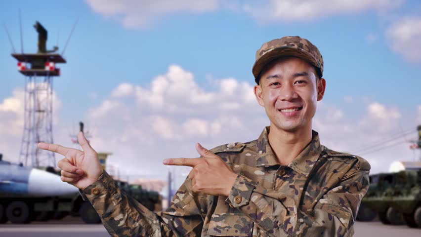 Close Up Of Asian Man Soldier Smiling And Pointing To Side While Standing At Military Camp