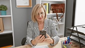 A joyful mature caucasian woman using a smartphone in a modern office setting