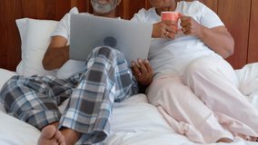 Animation of network of connections with icons over senior biracial couple using laptop in bed. Global connections, lifestyle, communication and digital interface concept digitally generated video. - Powered by Shutterstock - Get 15% off with code: PIKWIZARD15