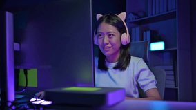A female gamer is streaming a game for many people to watch, A young game streamer plays games on her computer in bedroom at home, A young woman is having fun playing a game.