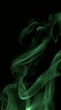 Vertical video, Green colored smoke slowly rising graceful twists upward. Colored smoke blowing from the up. Close up, isolated on black background