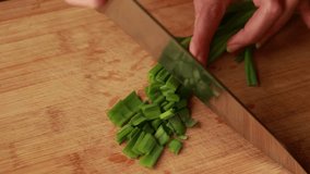 woman hands chopping green onion on wooden board close-up