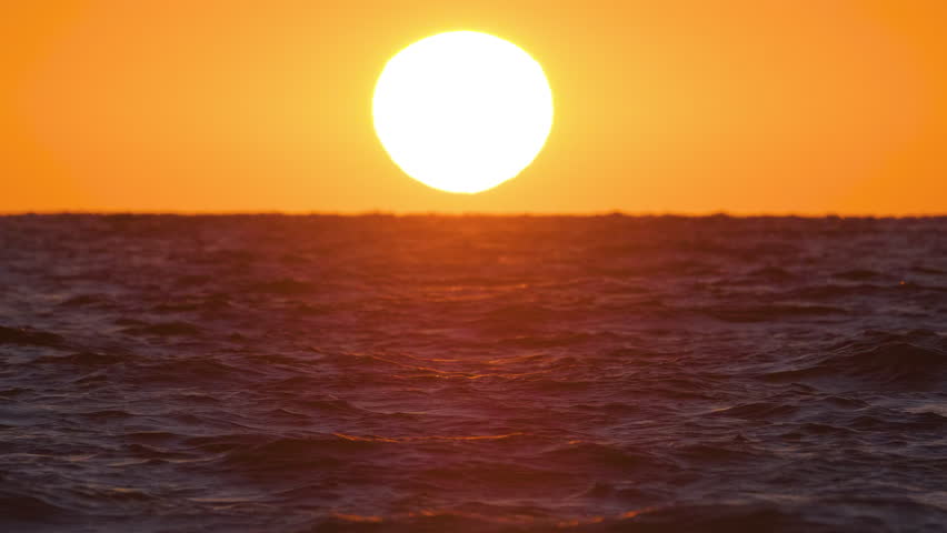 Ocean sunset. Big white sun on dramatic bright sky background, soft evening horizon over sea dark water