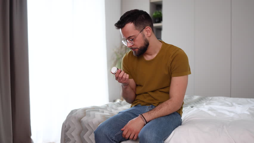 Young man feeling miserable and holding a bottle with antidepressants Royalty-Free Stock Footage #3454057569