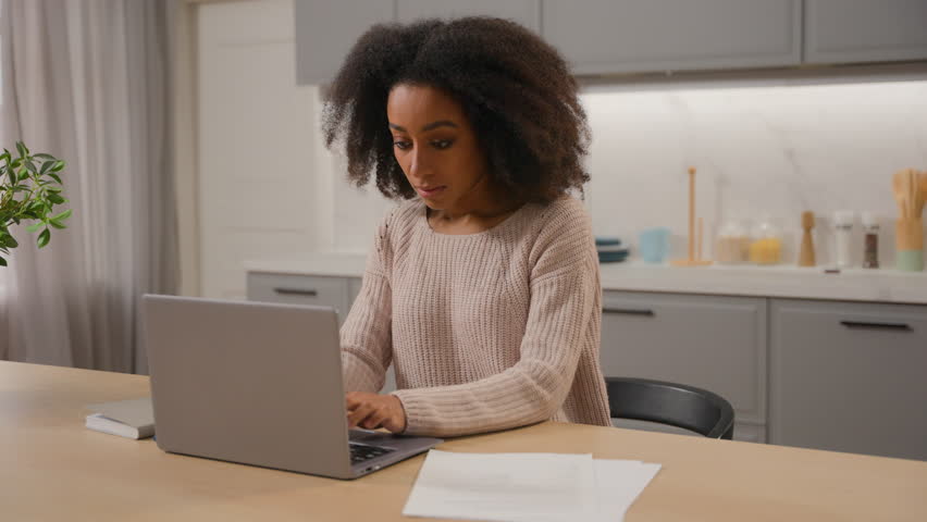 African American woman freelancer businesswoman working with papers documents at table in kitchen ethnic serious girl pay online utility bills domestic budget internet services on laptop pc at home Royalty-Free Stock Footage #3454205143