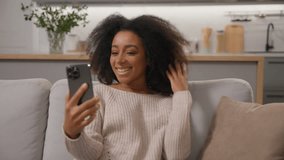 Happy smiling African american woman talking mobile phone smartphone online virtual meeting ethnic girl cheerful waving hand greeting record blog distant video call laughing with friends on home sofa - Powered by Shutterstock - Get 15% off with code: PIKWIZARD15