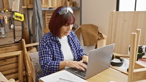 Concentrated senior hispanic woman working on a laptop in a woodworking workshop. - Powered by Shutterstock - Get 15% off with code: PIKWIZARD15