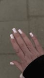 manicure video where the nails sparkle with a black sleeve from a jacket and on a background of gray asphalt
