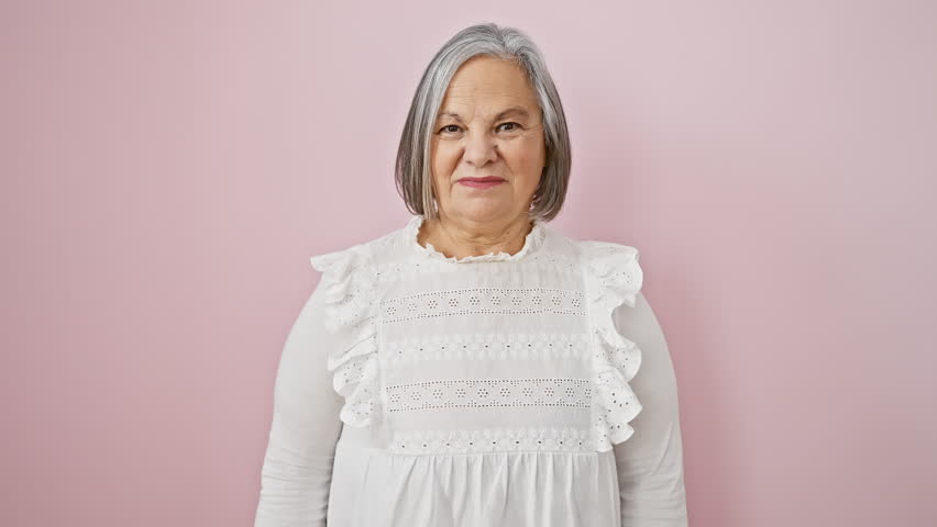 Joyous grey-haired, middle age woman in shirt, standing confidently with toothy smile, exuding positive energy over isolated pink background Royalty-Free Stock Footage #3454247353