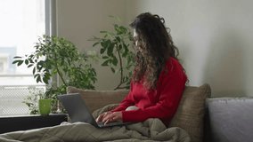Curly hair brunette woman working on a laptop from home, sitting on a couch and smiling with a mug of tea, with window and plant in the background.
4K, 50fps, 10bit from FX3 in Slog3