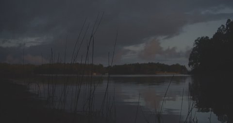 Wide shot of lake at dusk with branches in FG Stock Video