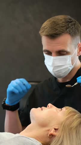 Dentist checks woman's teeth, wearing mask and gloves for hygiene. Royalty-Free Stock Footage #3454340087