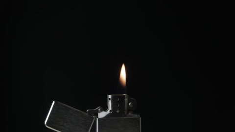 Open metal lighter zippo with flame on black background