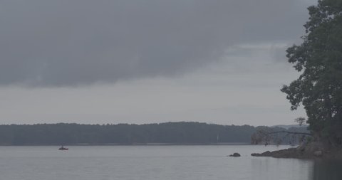 WS of lake with fisherman, overcast sky ஸ்டாக் வீடியோ